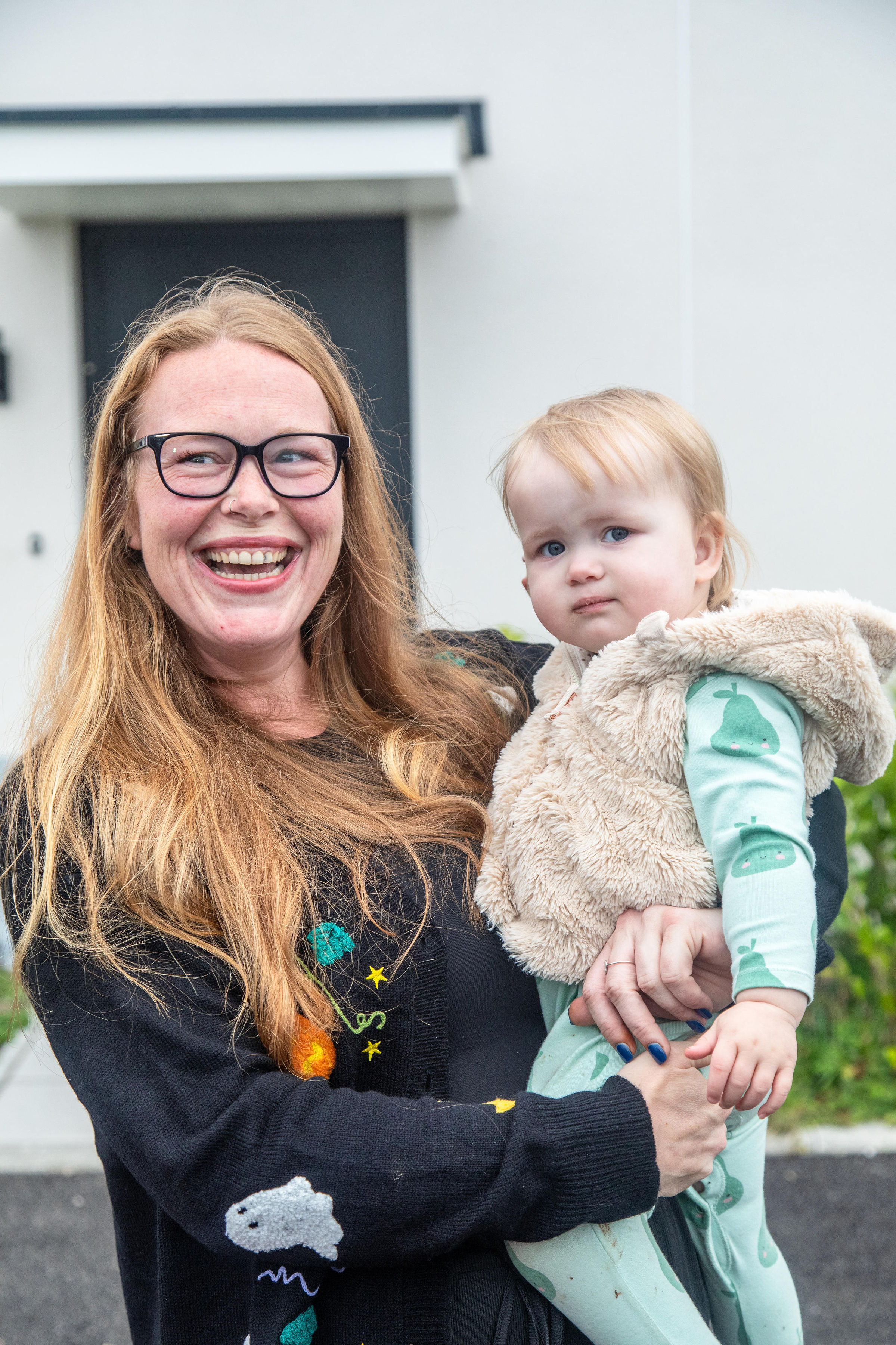 A LiveWest customer is holding her baby and laughing, looking very happy