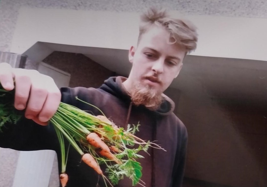 Connor holding the carrots he has grown at the scheme.
