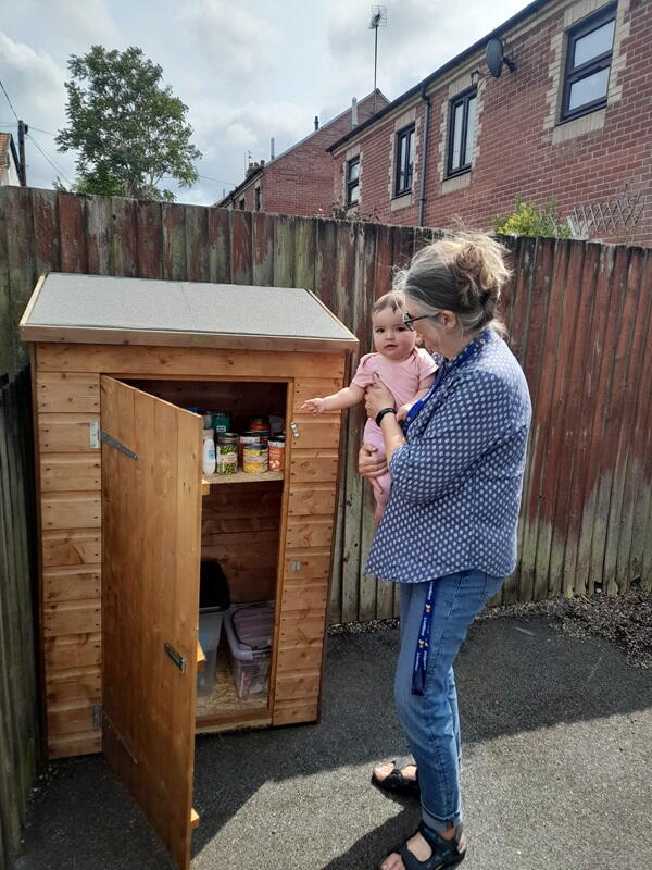 A colleague carrying a baby looking at the pantry.