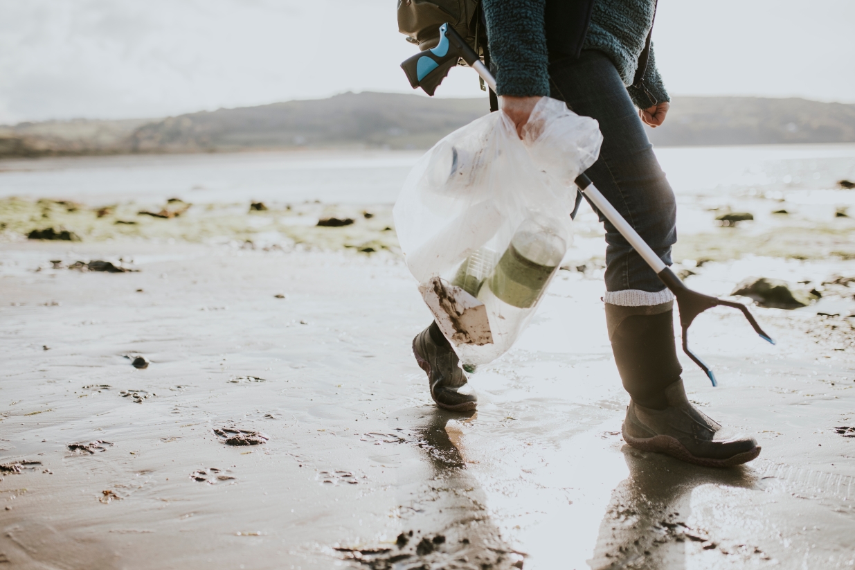 Person collecting rubbish at a beach