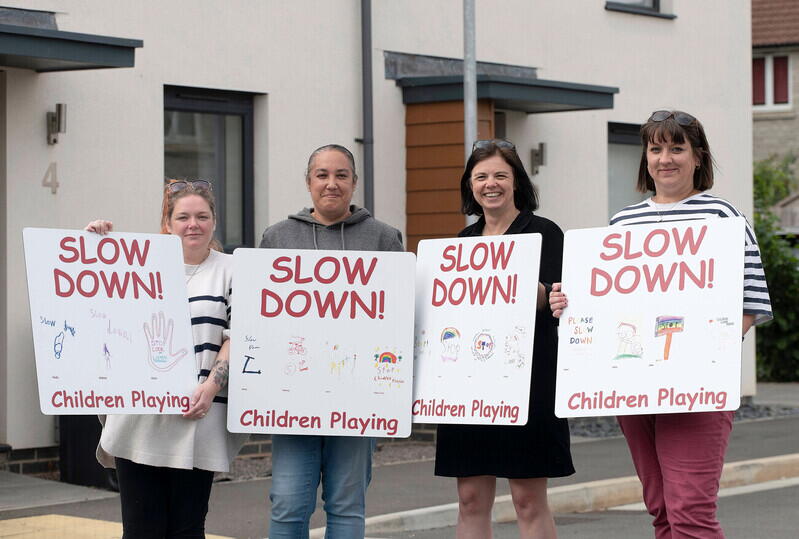 Three LiveWest residents holding the 'slow down' signs with our Community Connector, Shona Stone 
