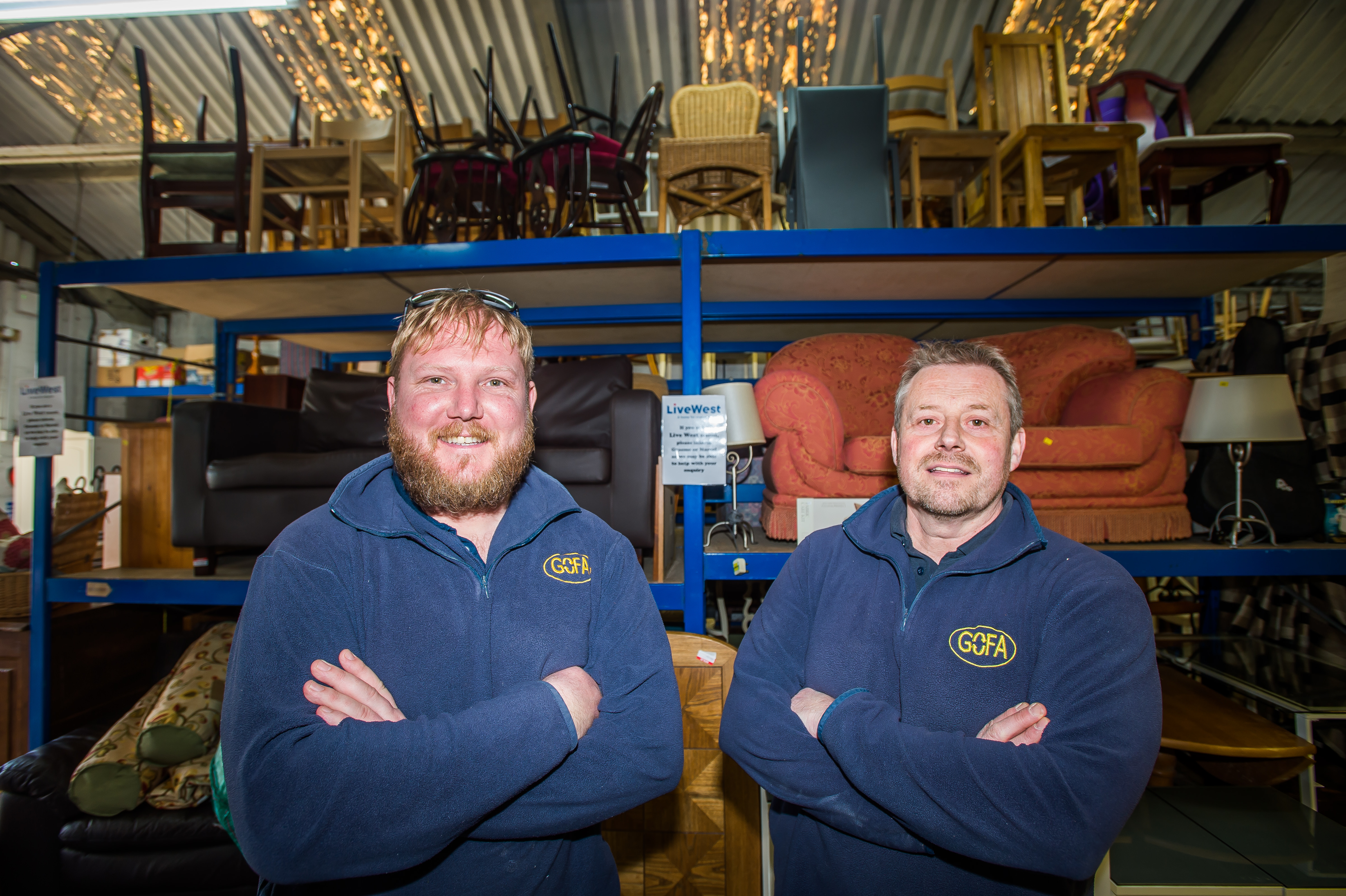 Two men smiling, standing in front of furniture