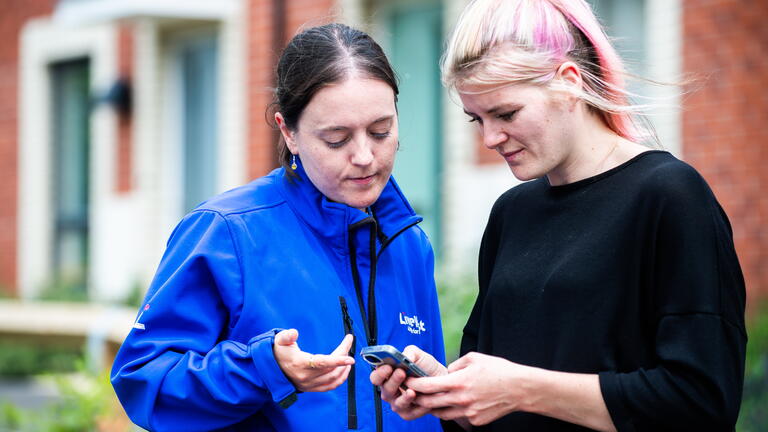 A LiveWest colleague and customer are looking at a phone screen