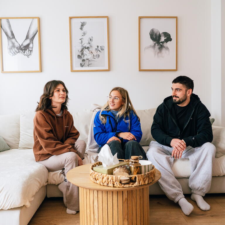 A LiveWest colleague is sat on a sofa with two customers smiling