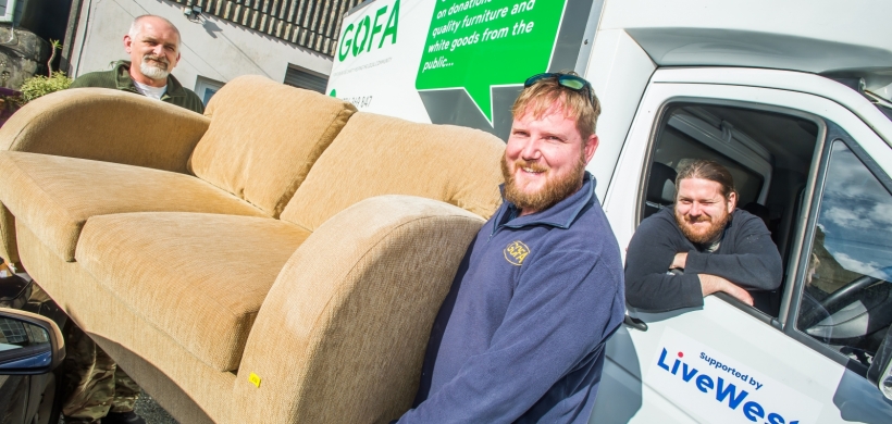 Men smiling and carrying a sofa