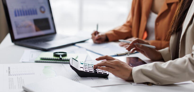 People sitting at desk with laptop and calculator