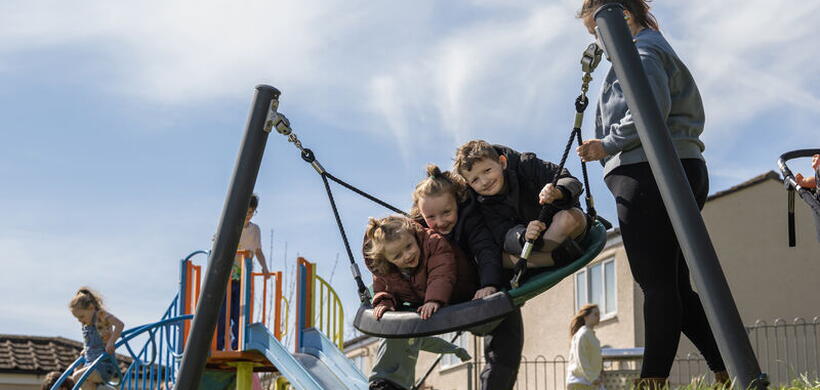 Three children swinging on a new round swing.