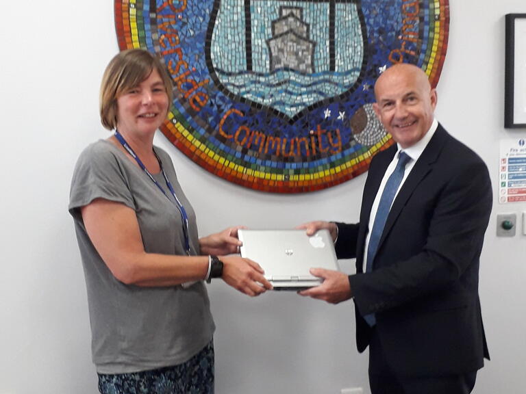 Justine a Community Connector handing over a laptop 