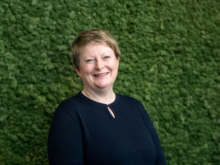 Glynnis smiling with a green leafy background