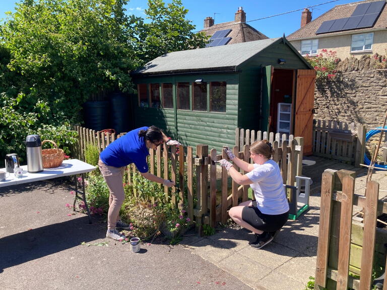 Our colleague volunteers paint a fence