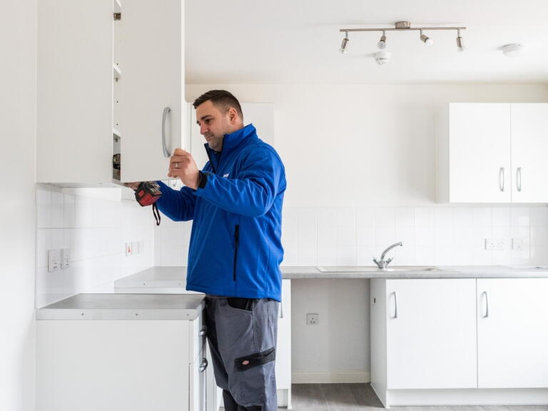 LiveWest colleague fixing kitchen cupboard door. 