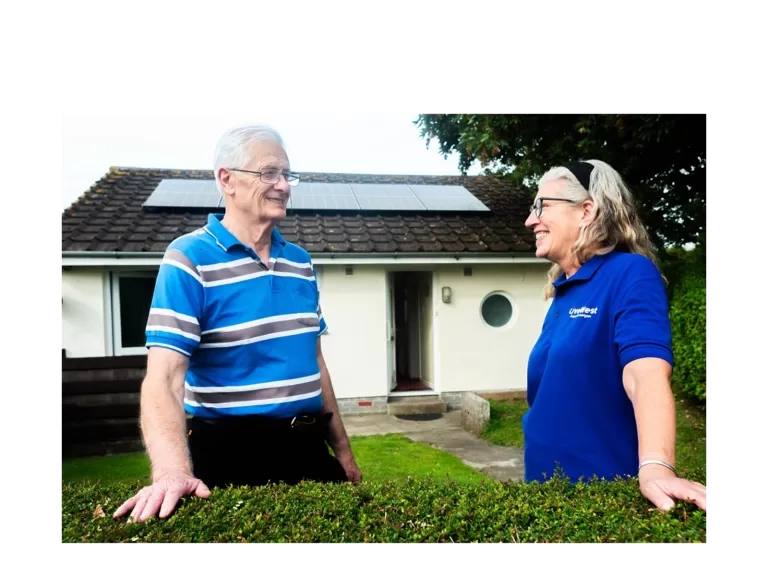 Tom Kingdom smiling outside of his home with new solar panels. 