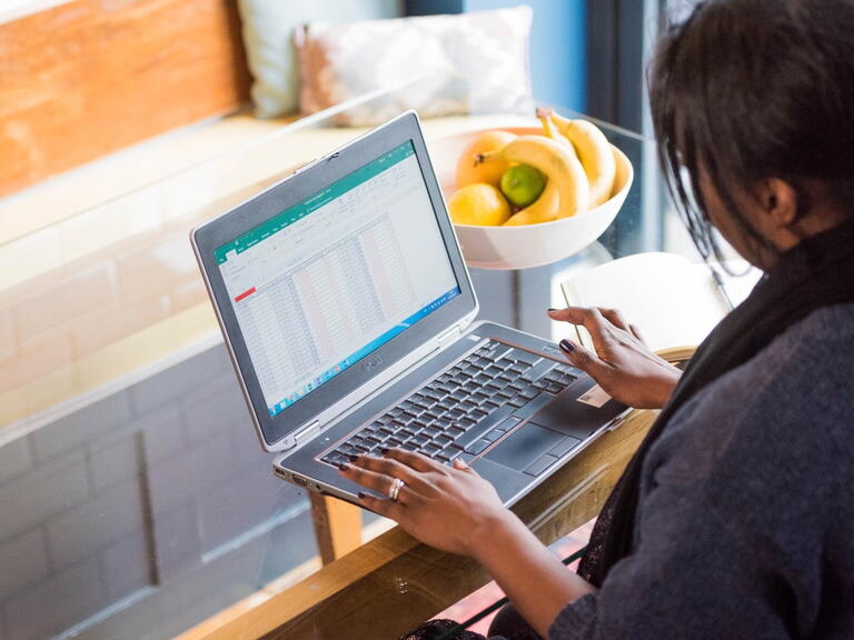 Someone using a laptop sat at a table. 