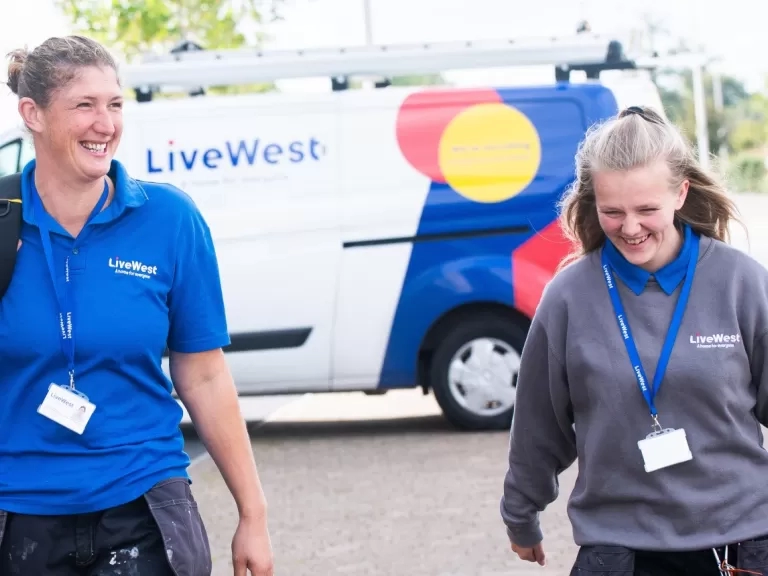 Gayle Bowden and a colleague walking with her tools from a van.