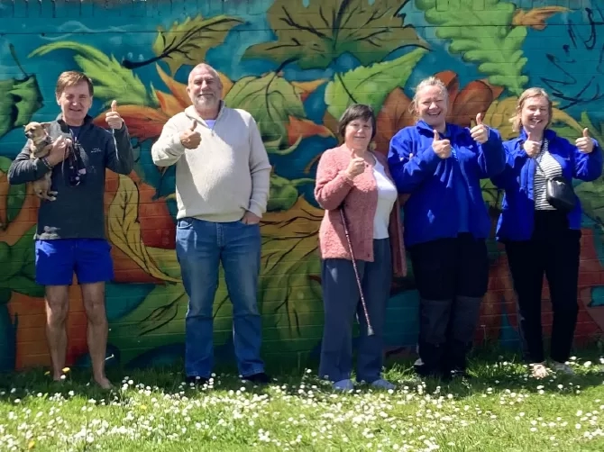 Local residents and LiveWest colleagues smiling in front of the new wall art.