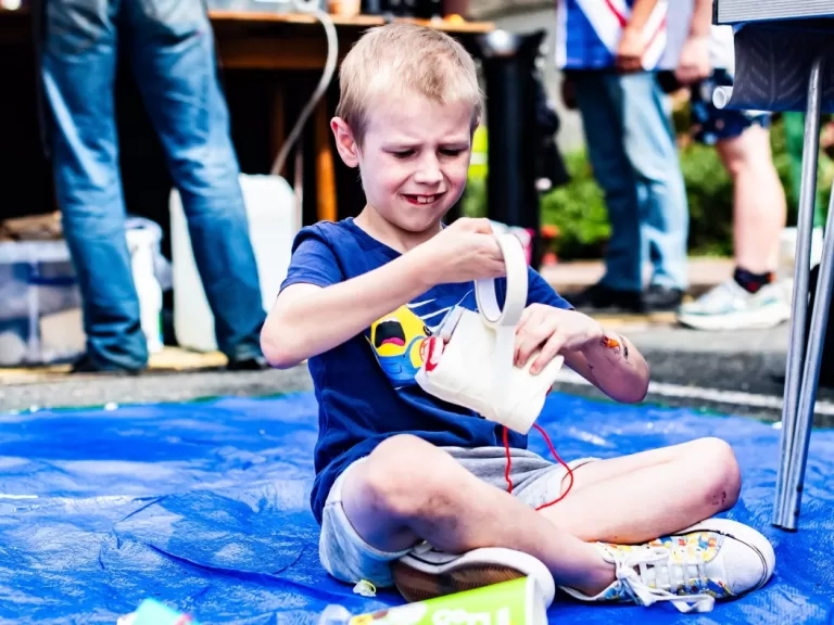 A boy sat on the floor making something with materials. 