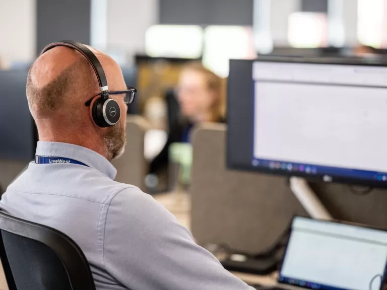 A LiveWest colleague speaking on the phone with a headset. 