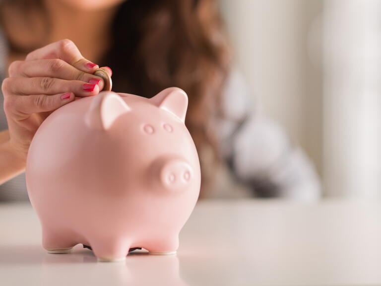 Someone putting money in a piggy bank. 