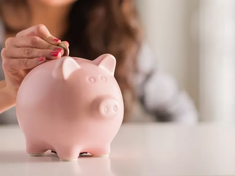 Someone putting money in a piggy bank. 
