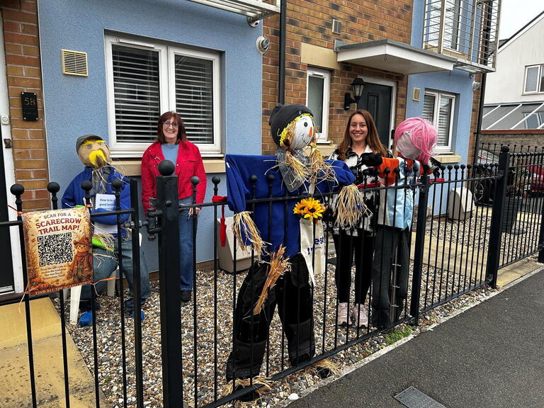 Two people stood with the scarecrows they had made.