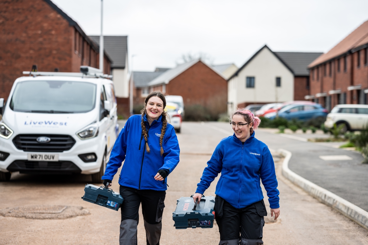 LiveWest colleagues walking along a road with toolboxes. 