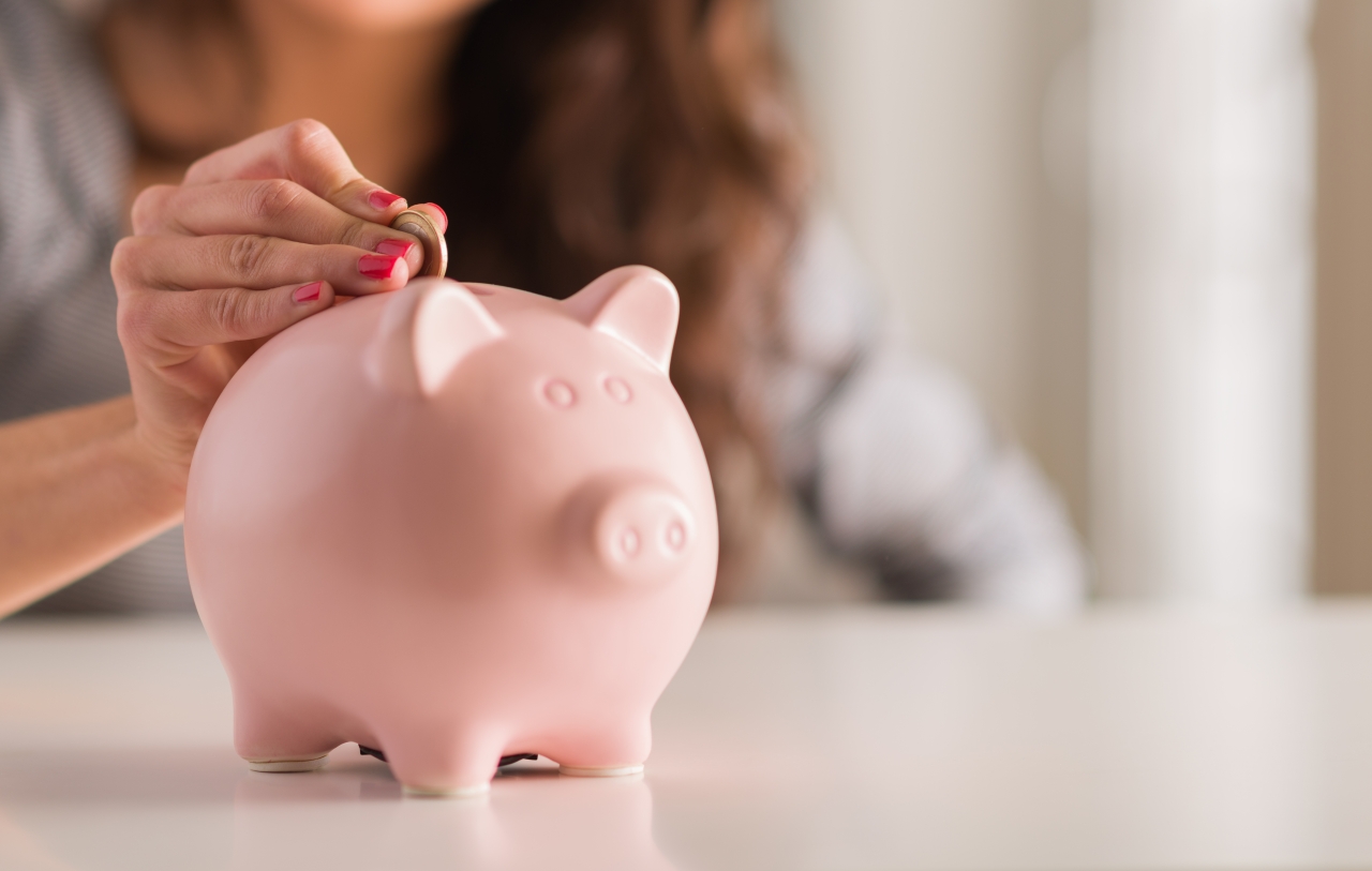 Someone putting money in a piggy bank.