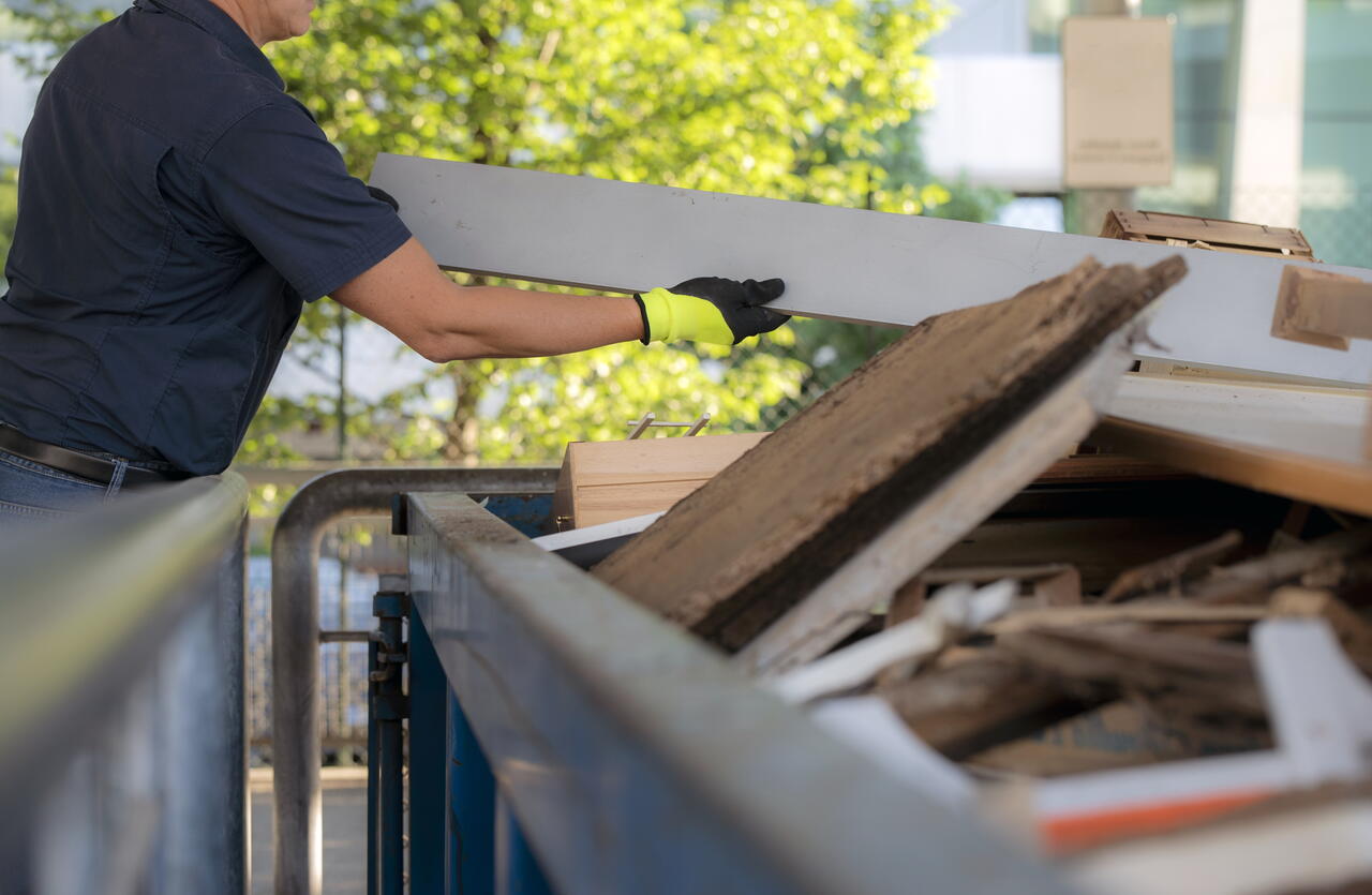 Image of a man putting large items in a skip