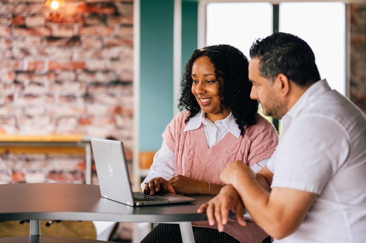 Image shows two people looking at a laptop