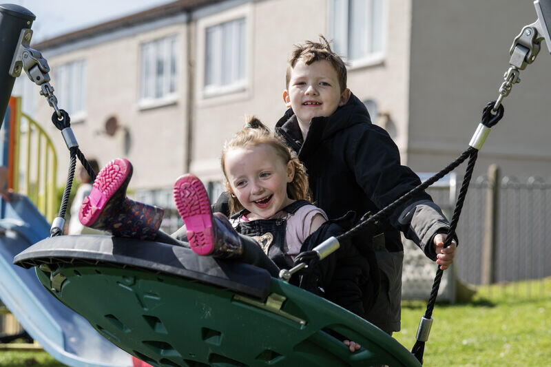 Image shows two children playing on a net swing in new play park.