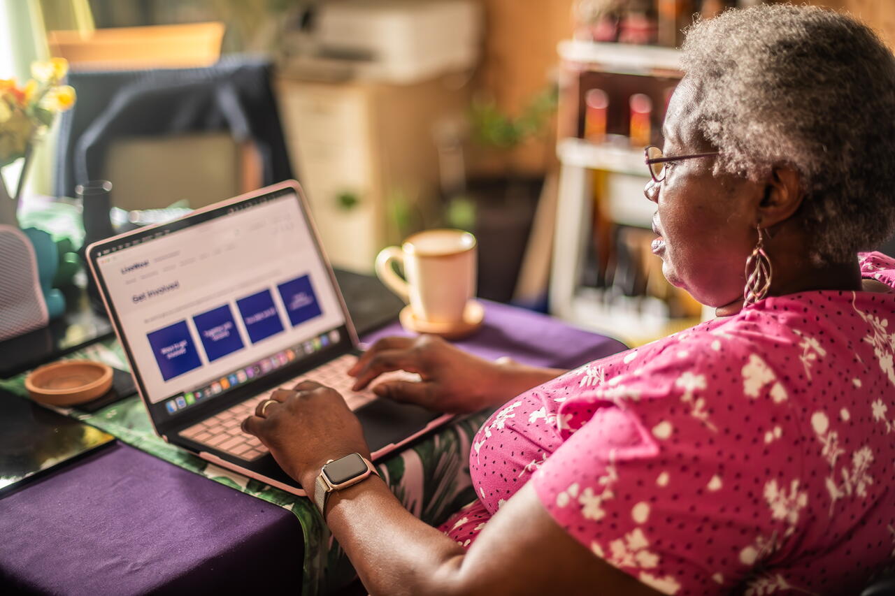 A person is using a laptop at a table in a warm, homey room.