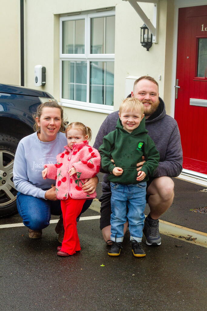 Caitlin, Chris and children smiling outside their front door.