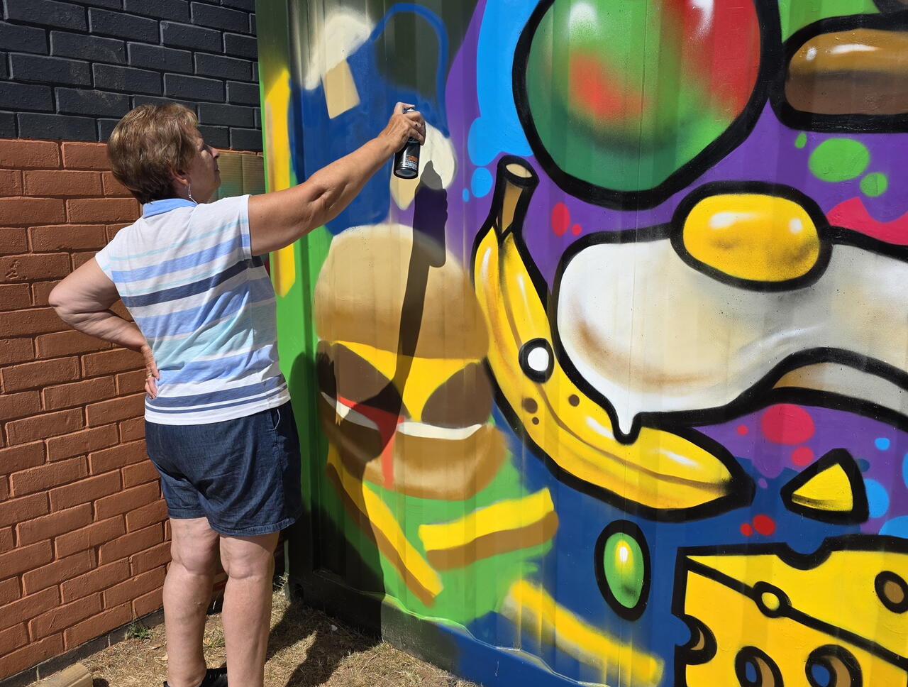 A woman is using spray paint on a wall