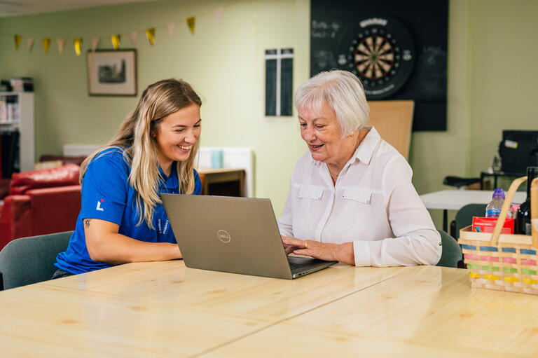 A LiveWest colleague and customer are sat at a computer smiling.