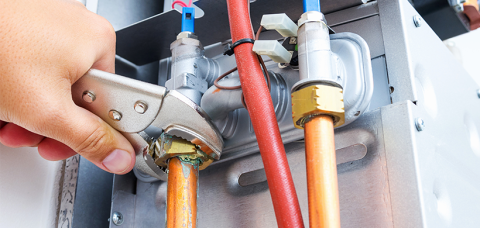 A person tightening a valve on a gas pipe.