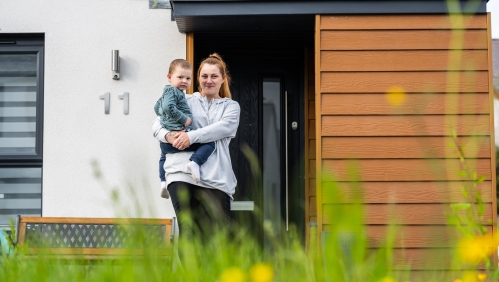 Woman with child outside a house.