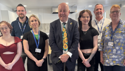 MP Steve Darling smiling with young people who live at Torbay and LiveWest colleagues.