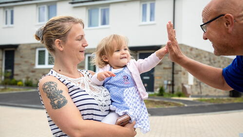 Image of a LiveWest colleague high-fiving a resident and her young daughter