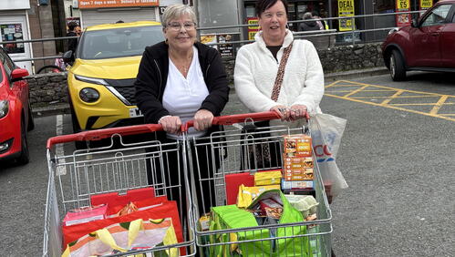 Image of two women smiling with trollies of food for the Help a Neighbour project