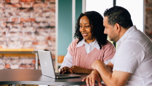 Image shows two people looking at a laptop