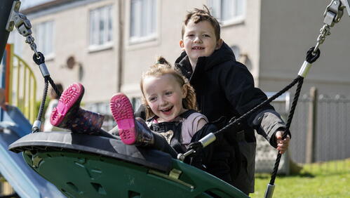 Image shows two children playing on a net swing in new play park.