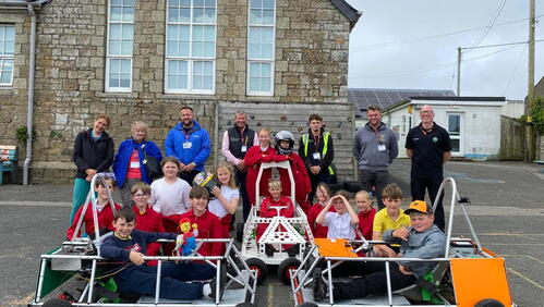 Group of people smiling in front of the Greenpower Goblin racing car