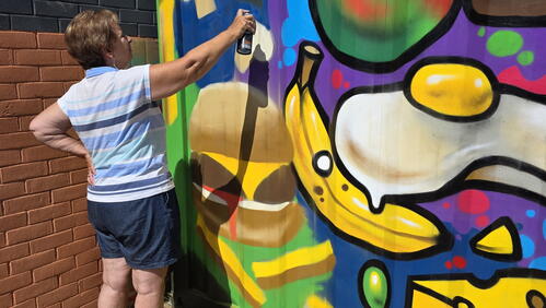 A woman is using spray paint on a wall