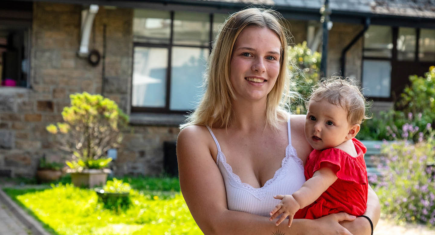 Female customer mother holding her baby in a sunny courtyard