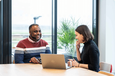 Customer speaking to a LiveWest colleague at a table with a laptop and cup of tea.
