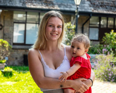 Female customer mother holding her baby in a sunny courtyard