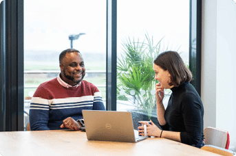 Customer speaking to a LiveWest colleague at a table with a laptop and cup of tea.